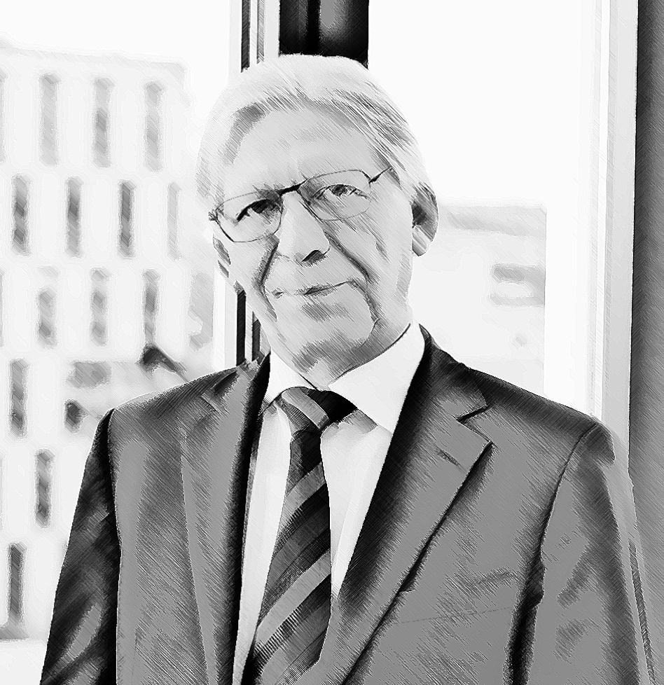 Mann in Anzug und Krawatte steht vor einem Fenster mit Blick auf ein Gebäude.